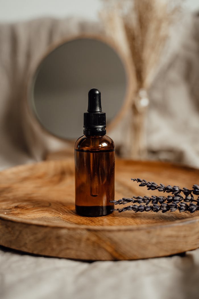 Amber glass dropper bottle on a wooden tray with lavender, ideal for skincare presentations.